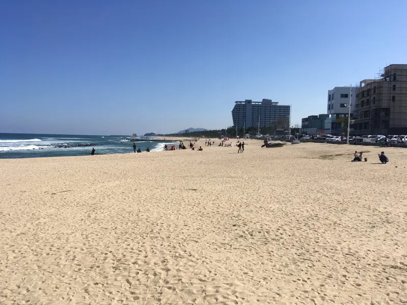 강문해변 모래사장과 파도, 멀리 보이는 건물