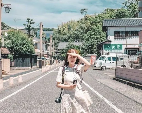 상점과 나무가 있는 거리에서 카메라를 메고 서 있는 여행자