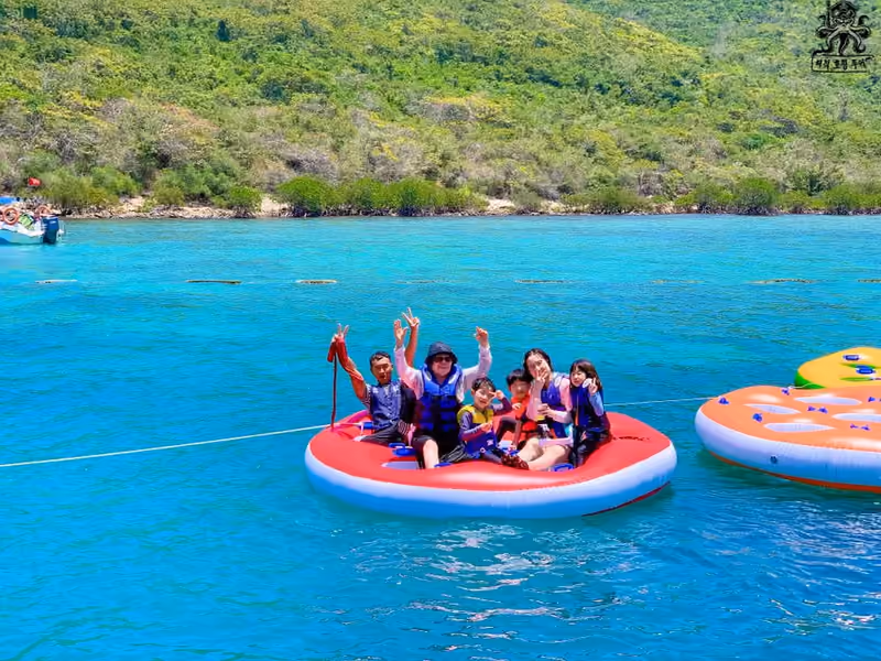 구명조끼를 입은 일행이 바다 위 큰 원형 튜브에 함께 앉아 있는 모습