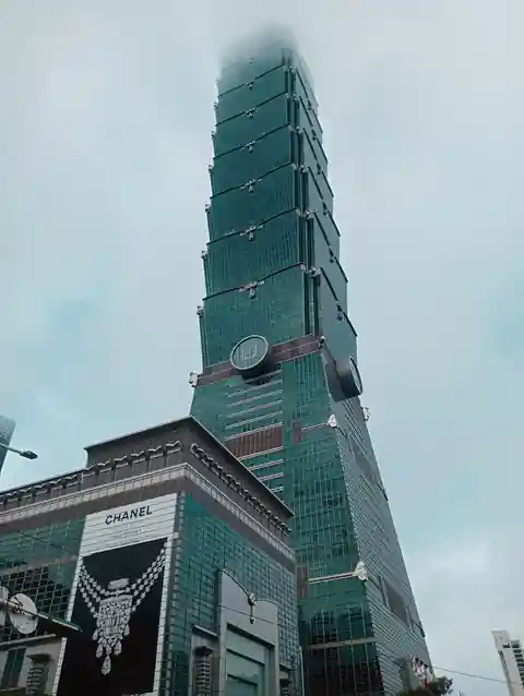 타이베이 101의 옥색 외벽과 아래쪽 건물을 올려다본 외관 사진.