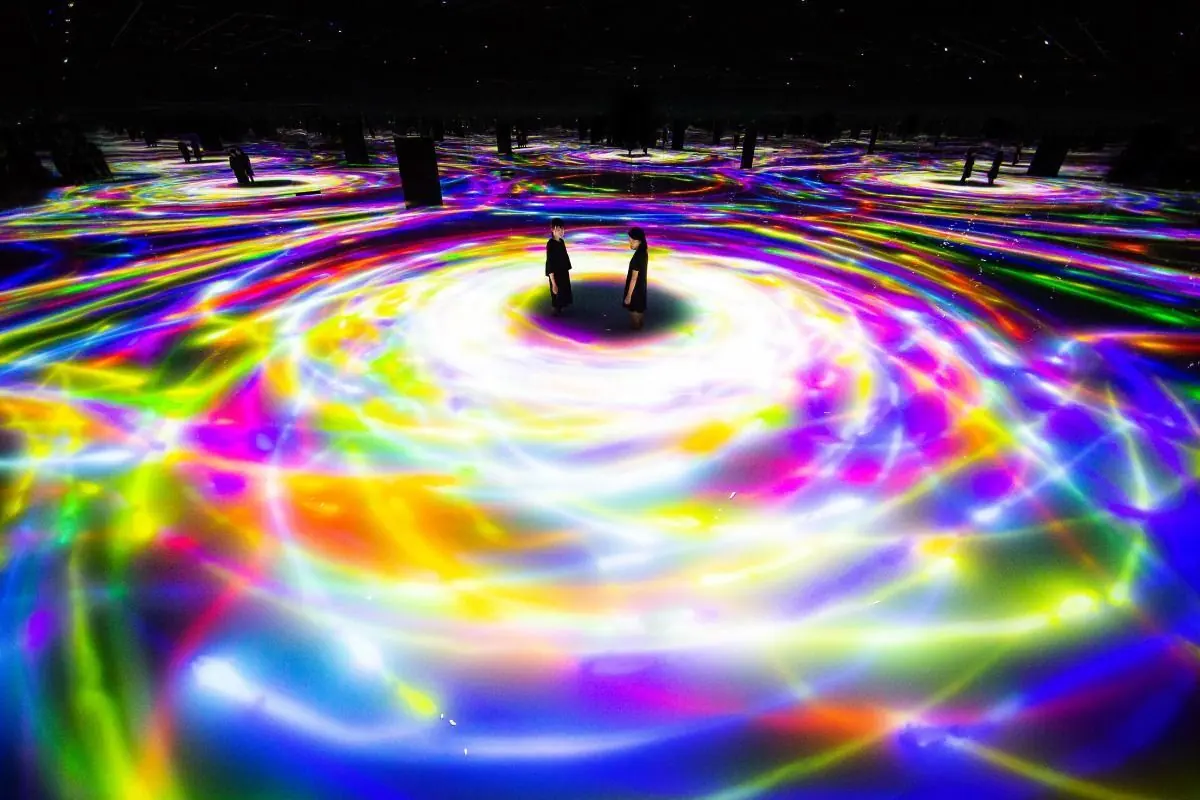 빛과 색이 바닥에 비치는 teamLab Planets 작품을 관람하는 방문객들