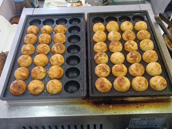 철판에 구워 둥글게 만든 타코야키 여러 개. 하나다코 지점 사진이 아닌 일반 메뉴 예시.
